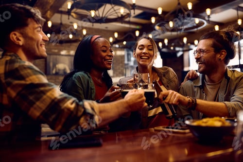 Preview: Cheerful friends toasting while drinking beer in a bar.