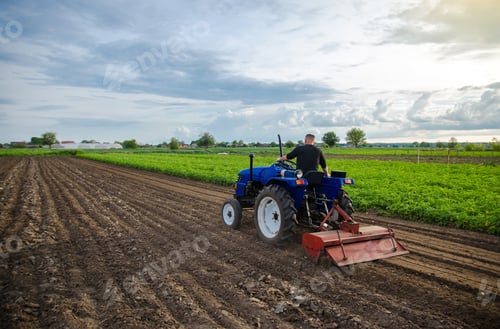 Preview: Farmer on tractor cultivates farm field.