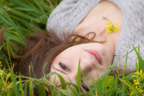 Preview: Woman Relaxing in Green Grass with Yellow Flowers