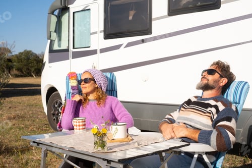 Preview: Couple relaxing outside their motorhome on a sunny camping trip enjoying a quiet outdoor breakfast