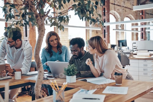 Preview: Group of young modern people in smart casual wear talking business ideas while working in the office