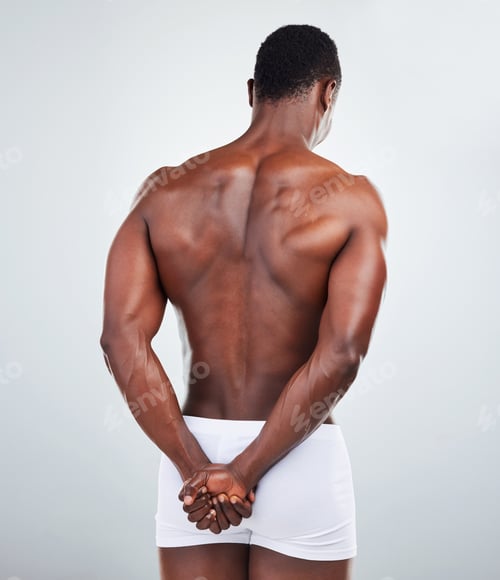 Preview: Rear view of one African American fitness model posing topless in a underwear and looking muscular.