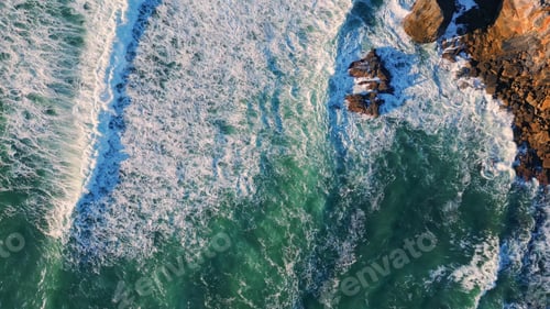 Preview: Top view waves barrelling to volcanic cliffs. Drone shot powerful sunny ocean