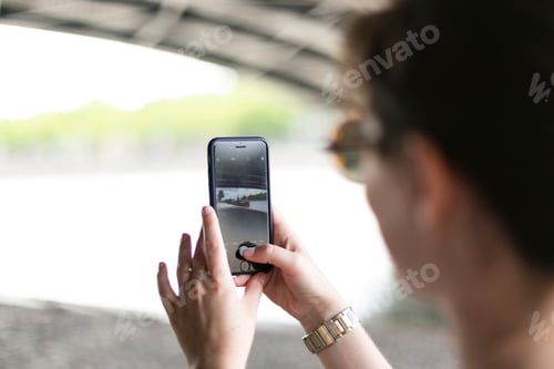 Preview: A woman takes a picture of a river using her smartphone