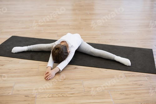 Preview: Little cute female lying down on twine on mat in bright spacious room.