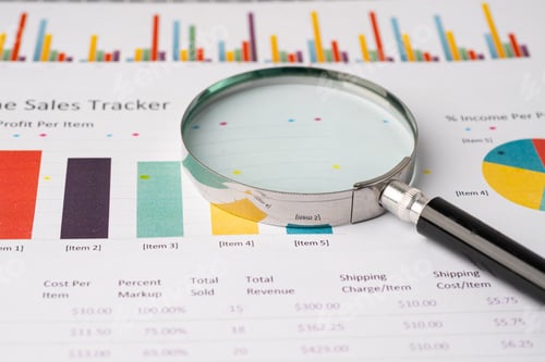 Preview: Magnifying glass on charts graphs paper.