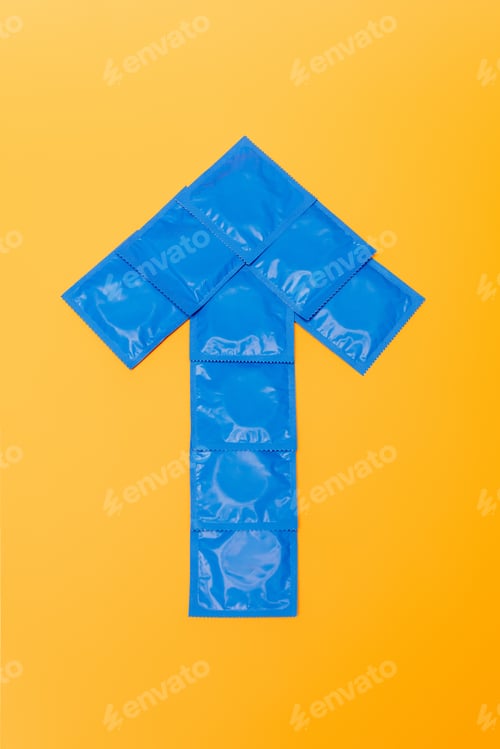 Preview: top view of arrow from packs with condoms isolated on orange