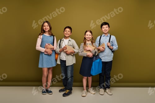 Visualização: Corpo inteiro de crianças pré-adolescentes multiétnicas alegres em roupas casuais, segurando mochilas e livros