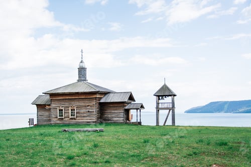 Preview: An old wooden log house Russian house and a bell tower on the bank of the river on a summer day