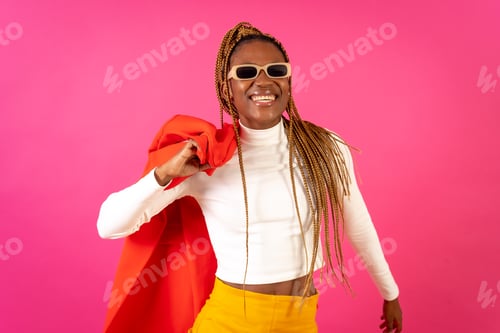 Preview: Black ethnic woman with braids on a pink background, wearing a red suit and white t-shirt smiling