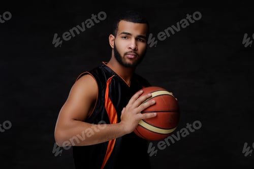 Preview: Young African-American basketball player in sportswear in a dark studio