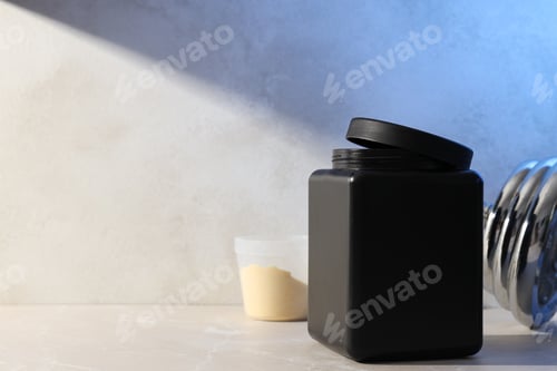 Preview: Black plastic jar, measuring cup with powder and dumbbell on light background, space for text