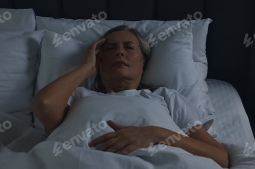 Preview: Woman suffering from headache in bed at night