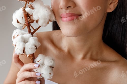 Preview: Asian young woman holding cotton flower near face