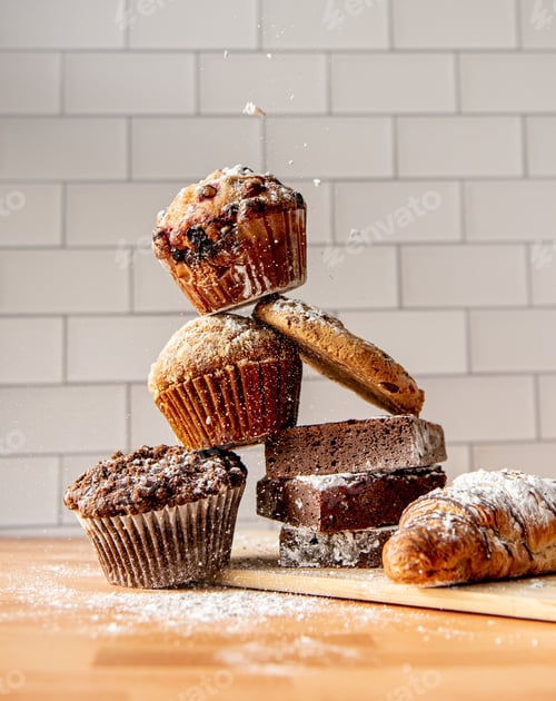 Preview: Closeup of a wooden table top with several freshly baked muffins and croissants
