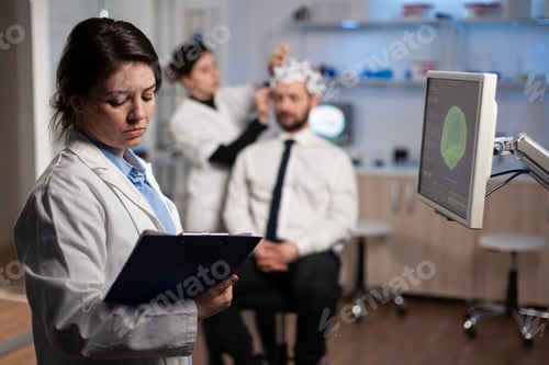 Preview: Medical neurologist woman adjusting eeg headset monitoring brain activity of man patient
