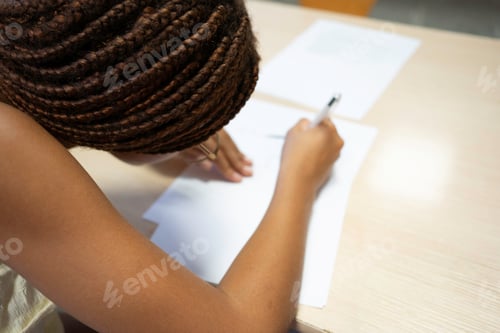 Preview: Afro student girl writing exam sitting at desk focusing