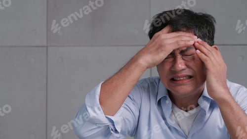 Preview: Asian old man with migraine headache. Man feel stressed and worried about health problems.