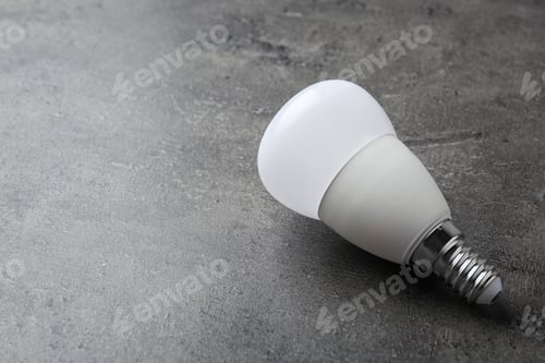 Preview: New modern lamp bulb on grey stone surface. Space for text