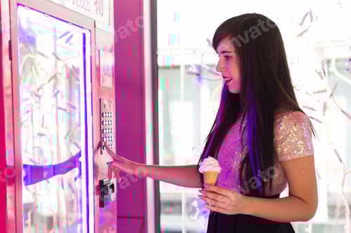 Preview: Pretty young woman using a modern beverage vending machine. Her hand is placed on the dial pad.