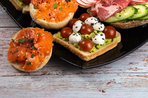 Preview: Assorted sandwiches with fish, cheese, meat and vegetables on a black plate