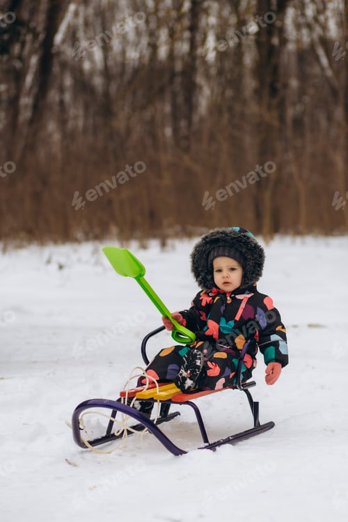 Preview: Little girl enjoying a sleigh ride. Child sledding. Toddler kid riding a sledge.