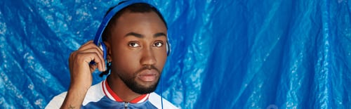 Preview: Handsome young man with headphones posing against a vibrant blue backdrop