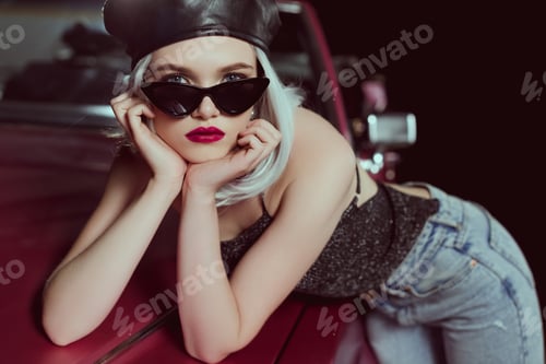 Preview: beautiful fashionable blonde girl in beret and sunglasses leaning at retro car and looking at camera
