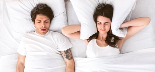 Preview: Young Woman Covering Ears While Man Sleeps and Snores in Bed