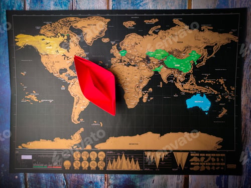 Preview: Top view of a paper ship on a world map placed on the wooden table