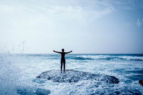 Preview: Freedom Woman outstretched arms at seaside mossy reef