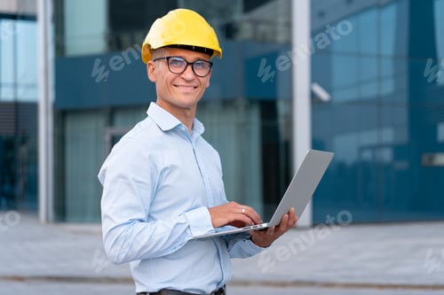 Preview: Young caucasian male architect protective helmet glasses laptop outdoor