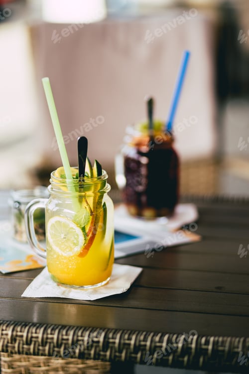 Preview: Vertical shot of ready mango and grape flavored lemonades on the bar.