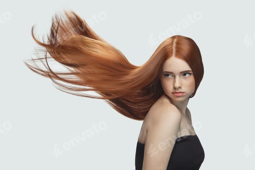 Preview: Beautiful model with long smooth, flying red hair isolated on white studio background