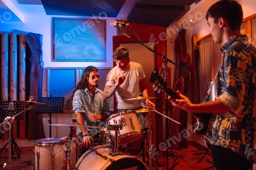 Preview: Musicians, drummer and guitarist, talking with their producers in music studio.