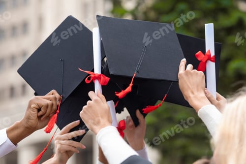 Preview: Graduation hats and diplomas in students hands, closeup