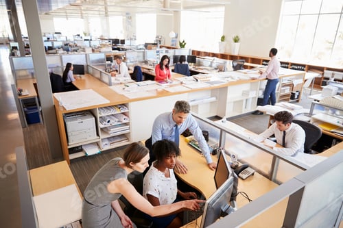 Preview: Colleagues working at a woman’s workstation in a busy office