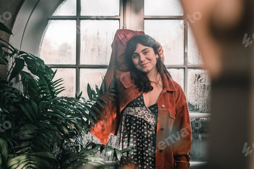 Preview: blue-eyed caucasian young woman in a pretty red jacket with earrings in her ears looking at the