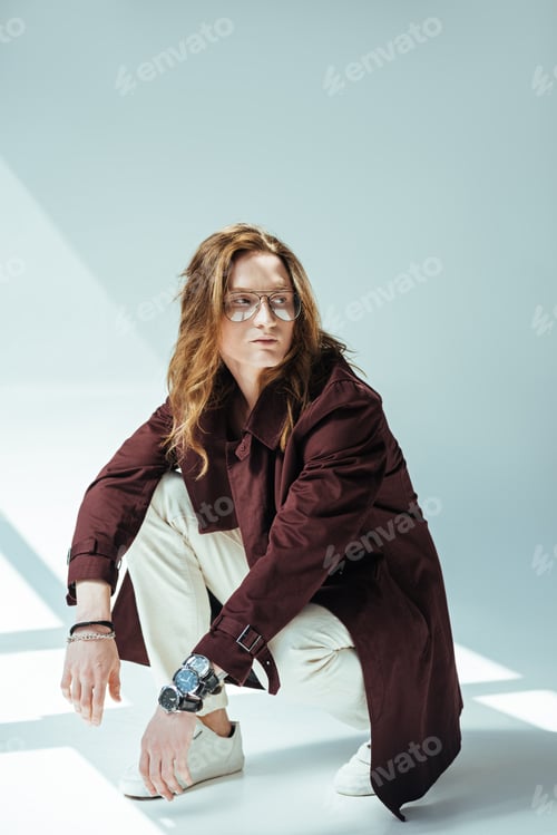 Preview: stylish man in eyeglasses posing in trench coat, on grey