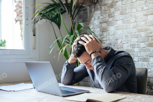Preview: Unhappy young Caucasian male worker in glasses look at laptop screen shocked by gadget