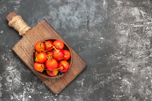 Preview: Top view of red cheries in a brown bowl and on cutting board on gray background