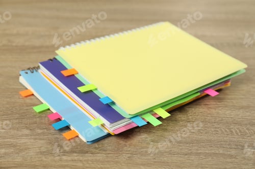 Preview: Notebooks with colorful tabs on wooden table, closeup