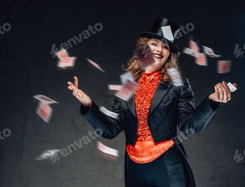 Preview: Funny female rogue from circus poses with flying cards in dark background