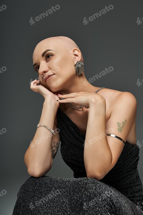 Preview: A reflective moment of a young woman with alopecia in a stylish black dress against a moody backdrop