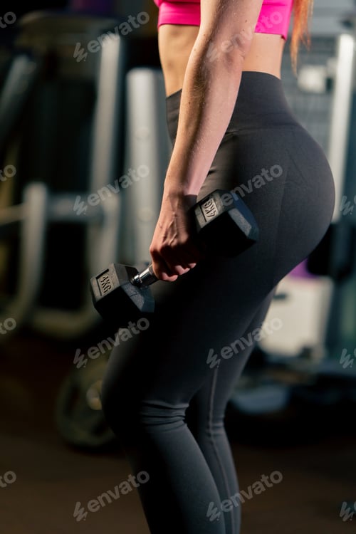 Preview: close up in the gym a girl with a ponytail in a pink top does lunges with dumbbells in her hands