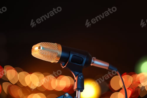 Preview: Microphone on stand against dark background with blurred lights. Bokeh effect