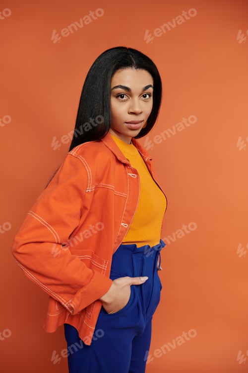 Preview: Stylish African American Woman Posing Confidently Against Warm Orange Background