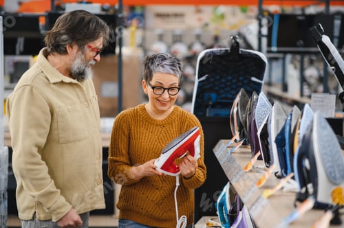 Preview: Senior couple choosing new flat iron in electronics store