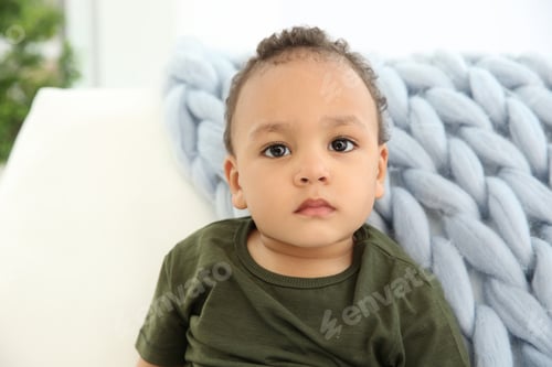 Preview: Cute African-American baby in stylish clothes on couch