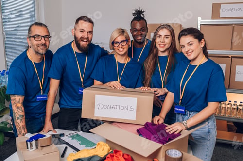 Preview: Diverse volunteers working in a charity donation center and packing clothes and food